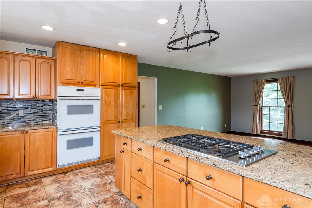 9981 Ridge Acres Lane Englewood, OH 45322 - Photo 15 of 73 This spacious kitchen offers a large island with cooktop, ample cabinetry, and modern appliances.