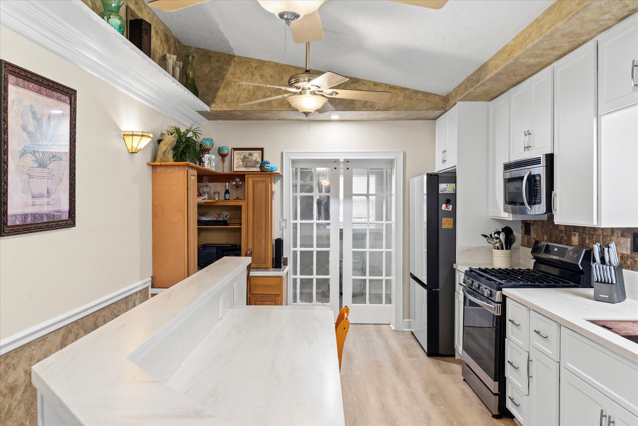 1320 6th Street Key West, FL 33040 - Photo 24 of 61 a kitchen with stainless steel appliances kitchen island granite countertop a refrigerator a stove a sink dishwasher and white cabinets with wooden floor