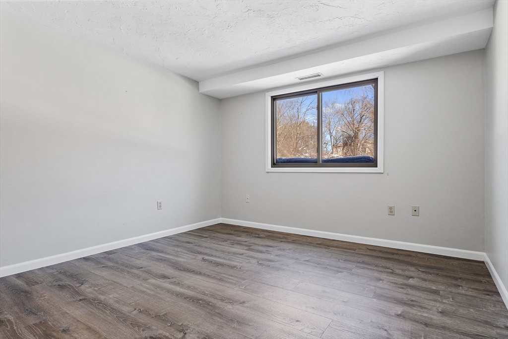 189 Littleton Road, Unit 10 Chelmsford, MA 01824 - Photo 14 of 19 a view of an empty room with wooden floor and a window