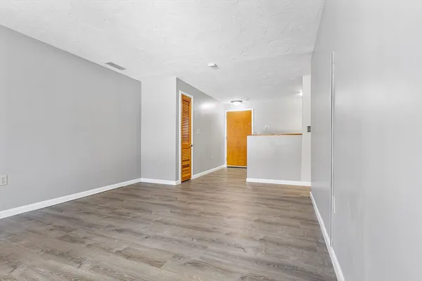 a view of an empty room with wooden floor and closet