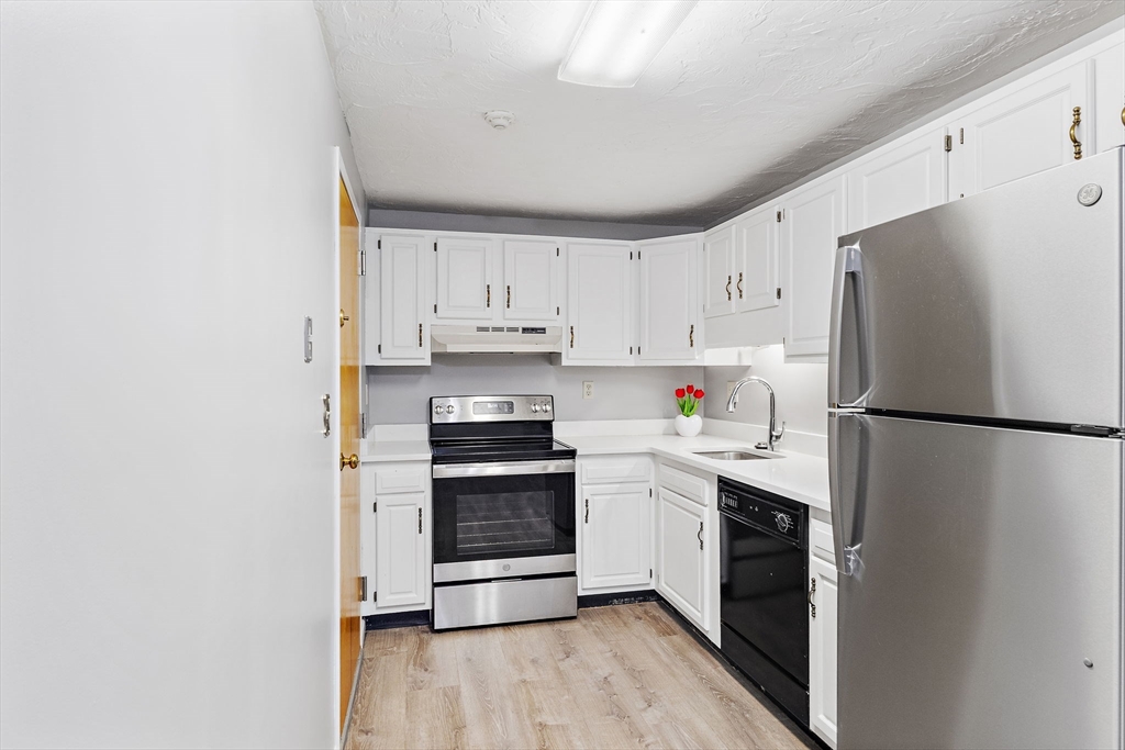 189 Littleton Road, Unit 10 Chelmsford, MA 01824 - Photo 10 of 19 a kitchen with a white refrigerator a sink and white cabinets