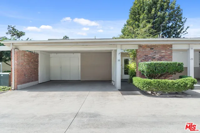 a view of road with card parked on side and retail shops