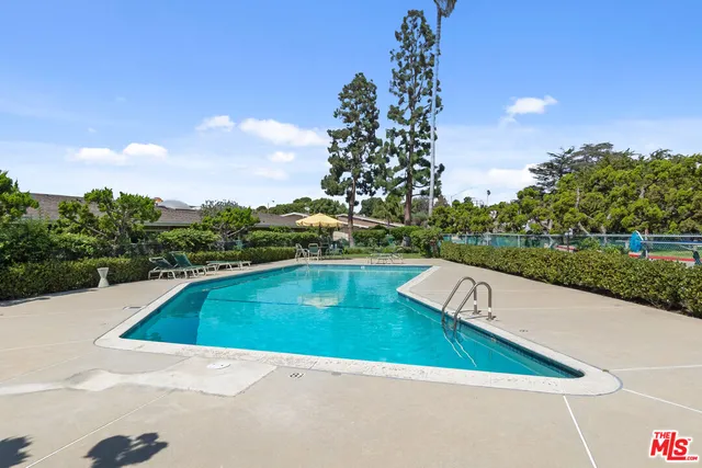 a view of swimming pool with seating area and trees in the background