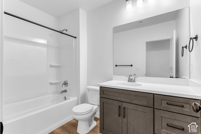 2503 North Scarlet Road, Unit 252 Eagle Mountain, UT 84005 - Photo 11 of 17 White bathtub with integrated shelving, brushed nickel fixtures, wood-finish flooring, dark wood-finish vanity with a white countertop, and a large wall-mounted mirror