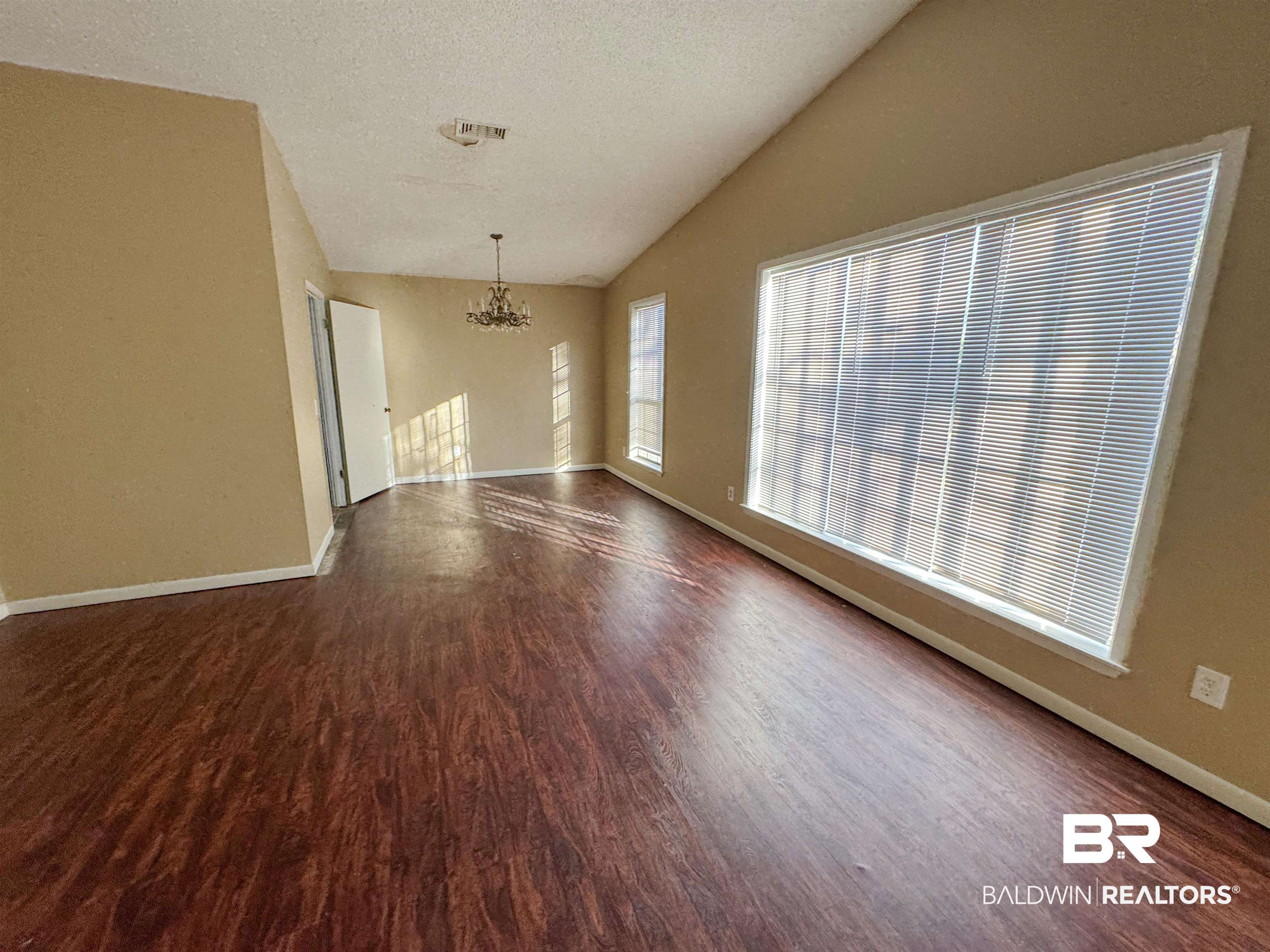 1227 Northgate Drive Atmore, AL 36502 - Photo 2 of 14 Unfurnished living room with a chandelier, lofted ceiling, a textured ceiling, and dark wood finished floors