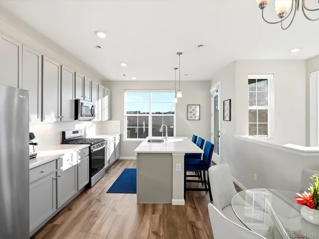 a large white kitchen with a stove a sink dishwasher and a refrigerator with wooden floor