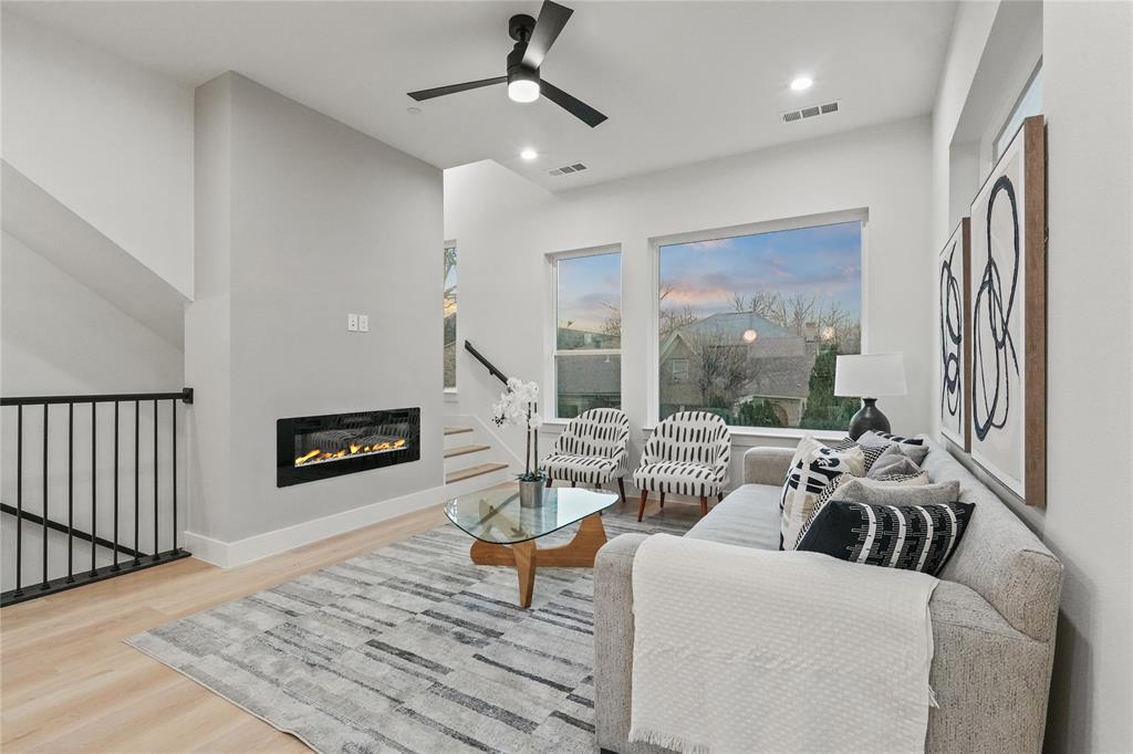 2031 North Prairie Avenue, Unit 101 Dallas, TX 75204 - Photo 7 of 23 Living area with a glass covered fireplace, wood finished floors, ceiling fan, recessed lighting, and a high ceiling