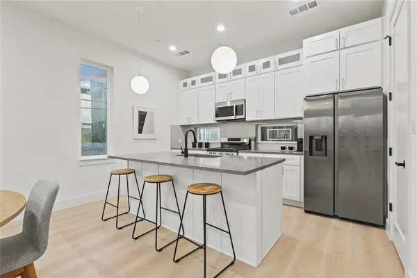 a kitchen with kitchen island granite countertop a sink cabinets and stainless steel appliances