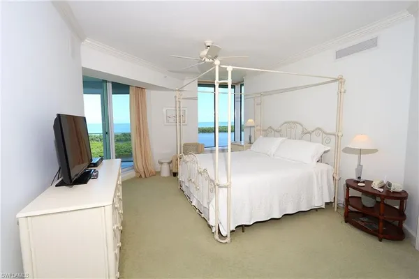 a bedroom with a bed and a flat tv screen on dresser