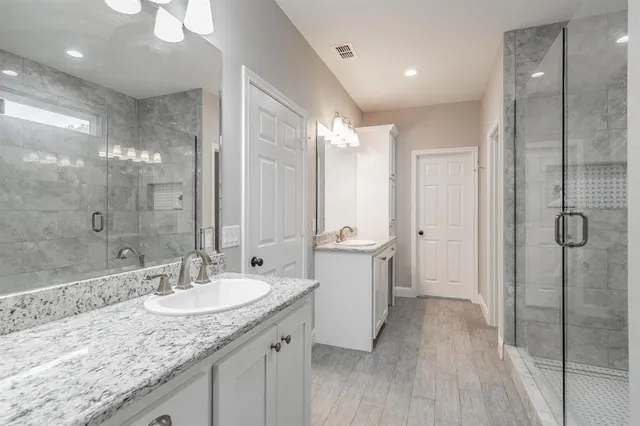 a bathroom with a sink double vanity granite tub shower and a mirror