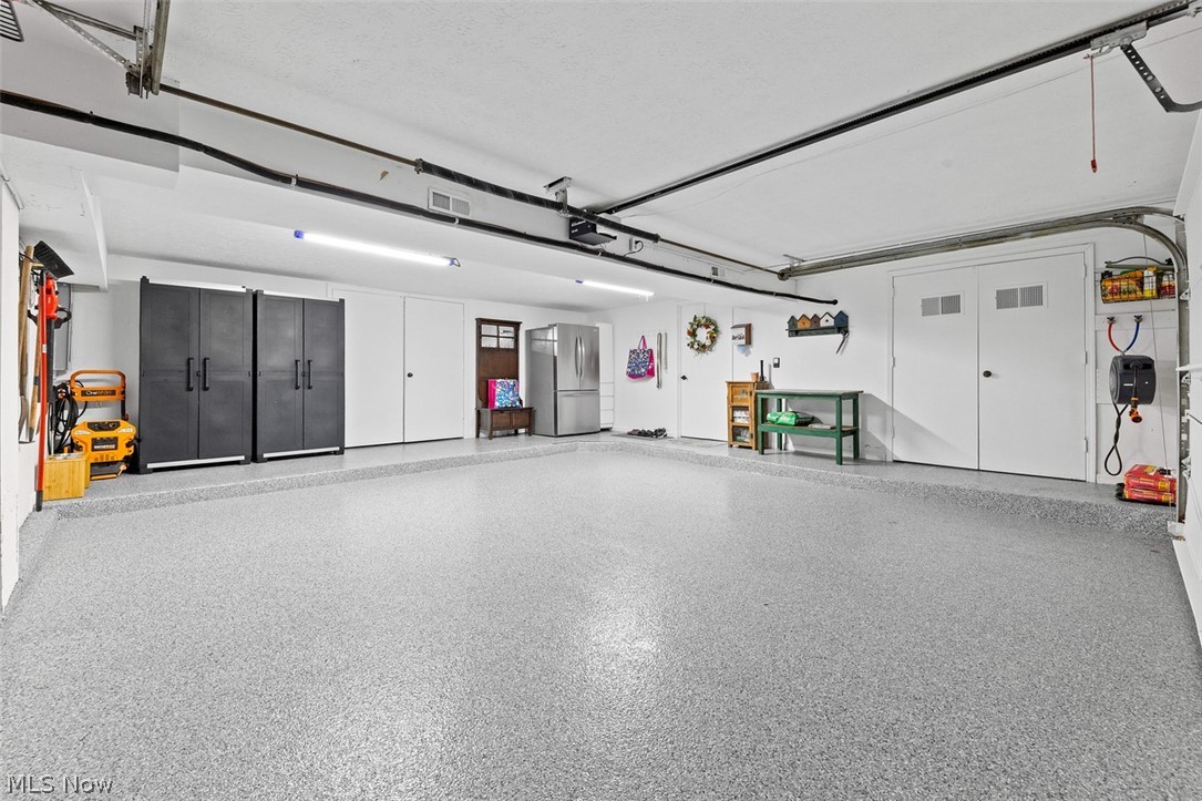 171 Granger Road, Unit 107 Medina, OH 44256 - Photo 34 of 41 Spacious garage featuring a durable epoxy floor coating, multiple storage cabinets, and bright overhead lighting with a work shop/ storage room in the back.