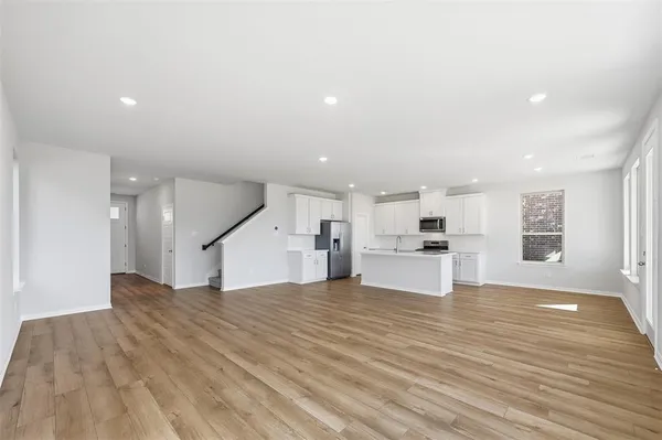 a view of a kitchen with kitchen island a sink wooden floor and a stove top oven