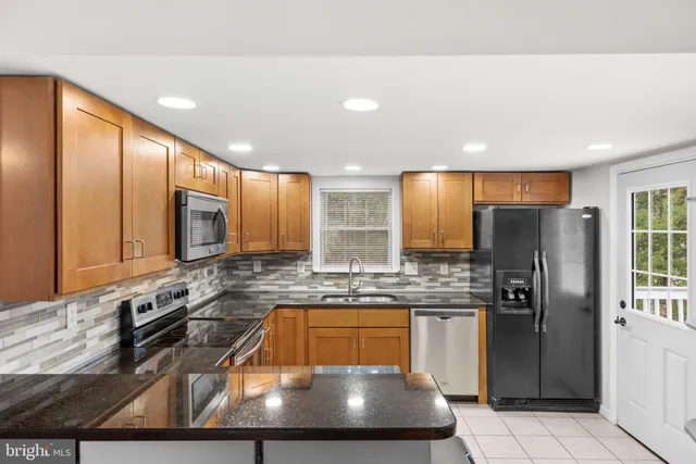a kitchen with stainless steel appliances granite countertop a sink refrigerator and cabinets