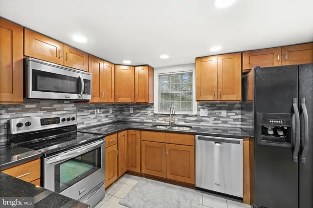 a kitchen with stainless steel appliances granite countertop a stove a sink and a microwave