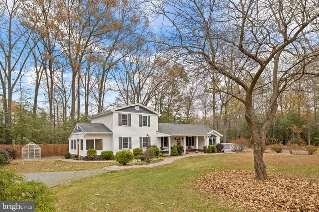 a front view of a house with yard and large trees