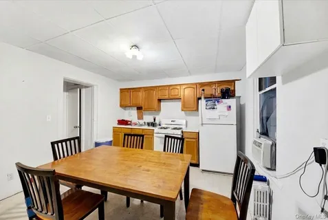 a open kitchen with stainless steel appliances granite countertop a stove a refrigerator a dining table and chairs with wooden floor