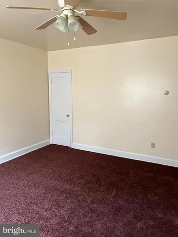 an empty room with a chandelier fan and a table