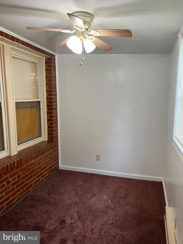 an empty room with a chandelier fan and windows