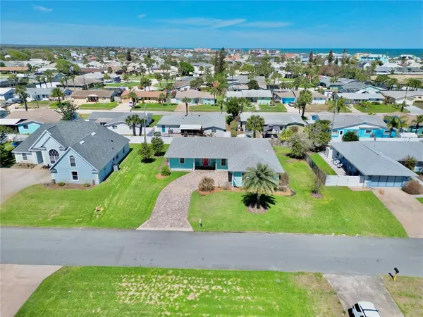 an aerial view of a city with lots of residential buildings ocean and mountain view in back