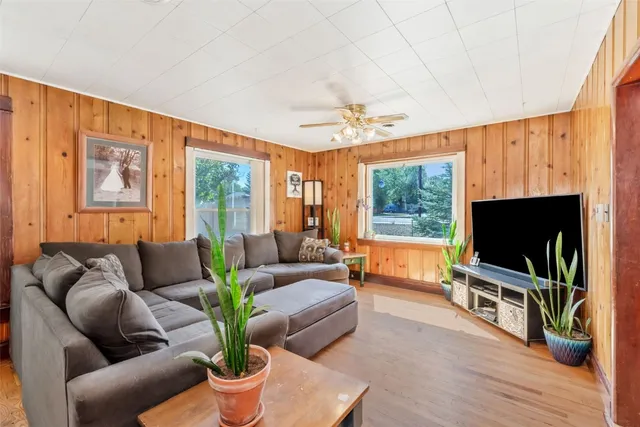 a living room with furniture a flat screen tv and a floor to ceiling window