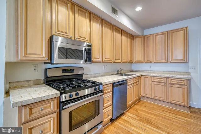 a kitchen with stainless steel appliances granite countertop a stove a sink and a microwave