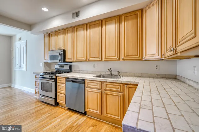 a kitchen that has a stove and a wooden floor