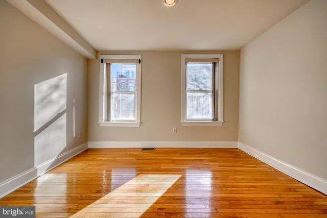 a view of an empty room with wooden floor and closet