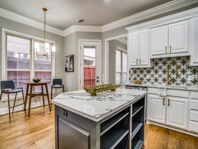 a kitchen with stainless steel appliances granite countertop a stove a sink and white cabinets with wooden floors