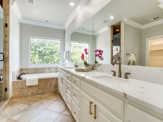 a bathroom with a granite countertop sink mirror bathtub and next to a window
