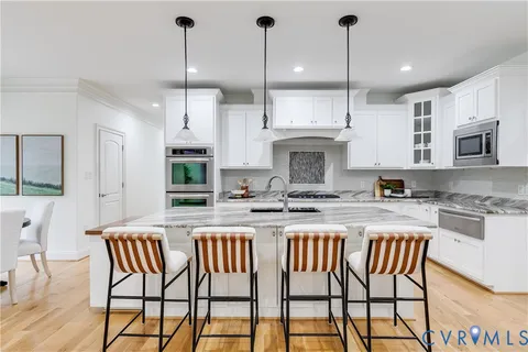 a kitchen with stainless steel appliances granite countertop a kitchen island a stove a table and chairs