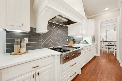 a kitchen with a stove and wooden floor