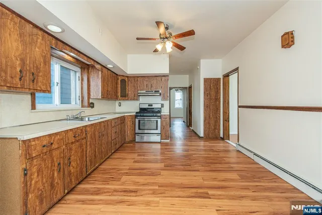 a large kitchen with wooden floor and stainless steel appliances