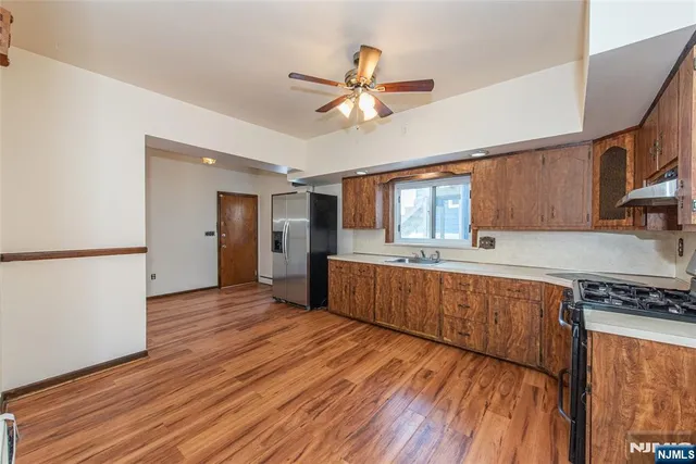 a kitchen with stainless steel appliances granite countertop a refrigerator a stove and a wooden floors