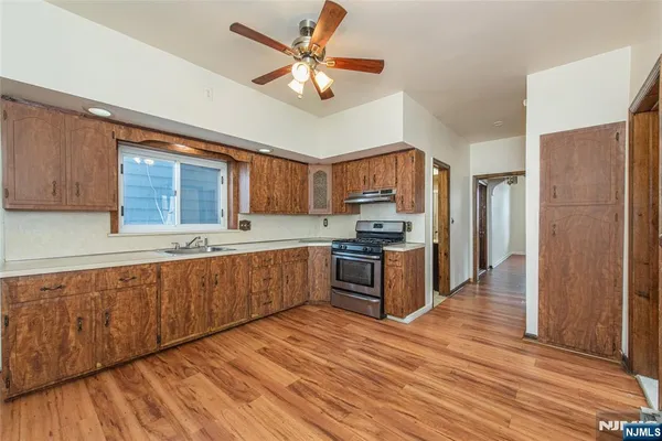 a kitchen with stainless steel appliances kitchen island granite countertop a refrigerator a sink dishwasher a stove with wooden cabinets and floor