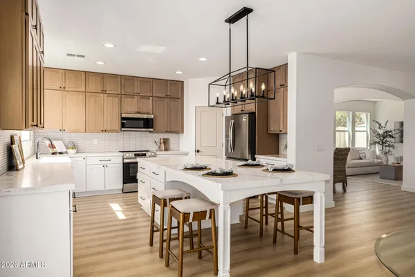 a kitchen with stainless steel appliances kitchen island granite countertop a stove a sink a dining table and chairs with wooden floor