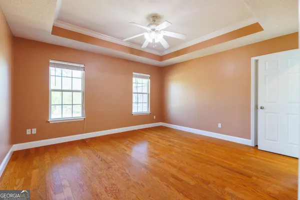 an empty room with windows and ceiling fan