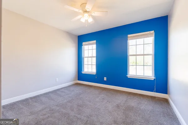 an empty room with windows and ceiling fan