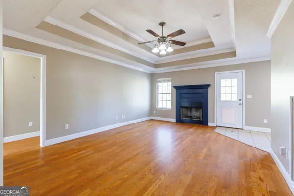 a view of an empty room with window fireplace and wooden floor