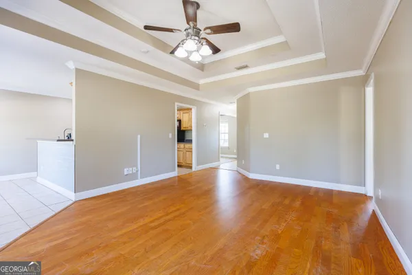 a view of a big room with wooden floor and a chandelier fan