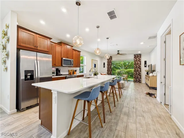 a kitchen with stainless steel appliances kitchen island a table chairs refrigerator and microwave