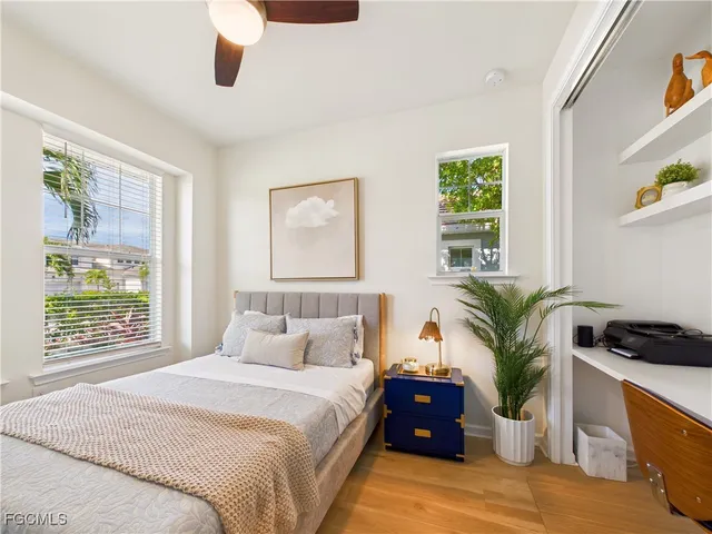 a bedroom with a large bed and a large window with potted plants