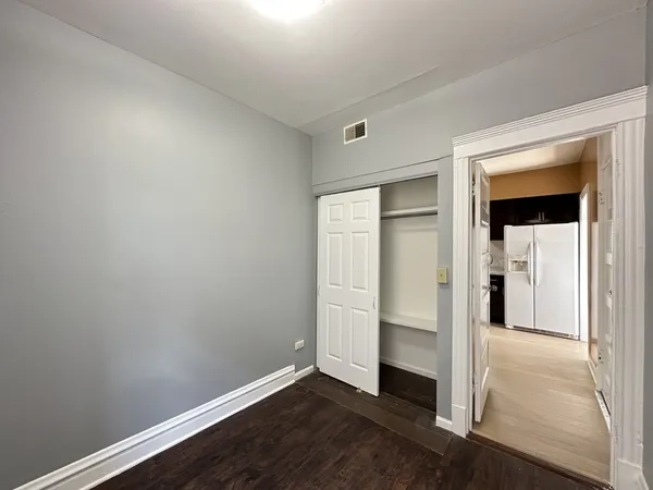 an empty room with wooden floor closet and windows
