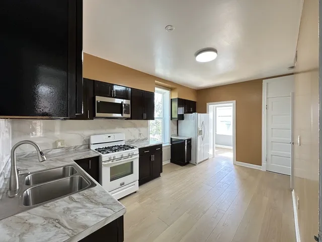 a kitchen with stainless steel appliances granite countertop a sink and a stove top oven with wooden floor