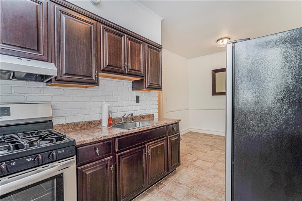 106 Village Road South Brooklyn, NY 11223 - Photo 23 of 42 a kitchen with stainless steel appliances granite countertop a stove and a refrigerator