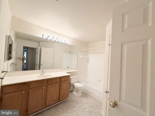 a spacious bathroom with a double vanity sink toilet mirror and bathtub