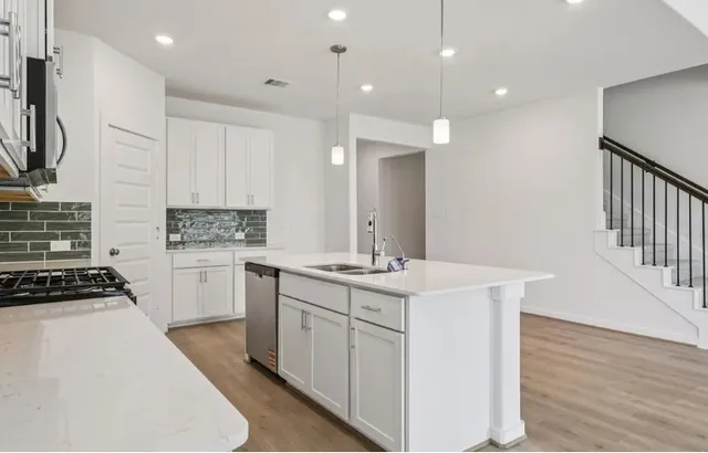 a kitchen with a sink stove and wooden floor
