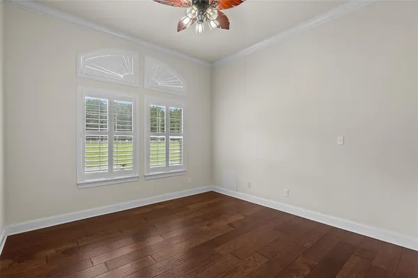 an empty room with wooden floor chandelier and window