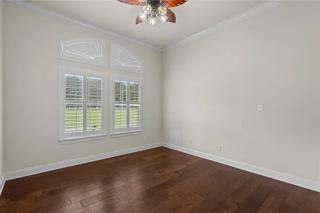 an empty room with wooden floor chandelier and window