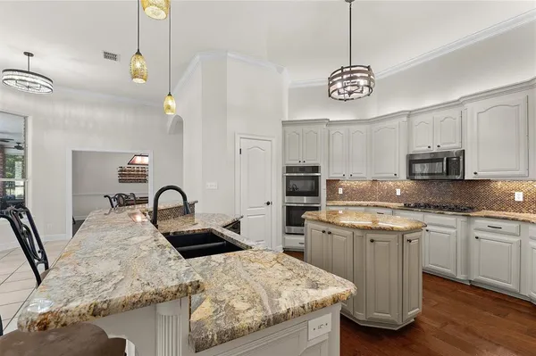 a kitchen with stainless steel appliances granite countertop a sink a stove center island and cabinets