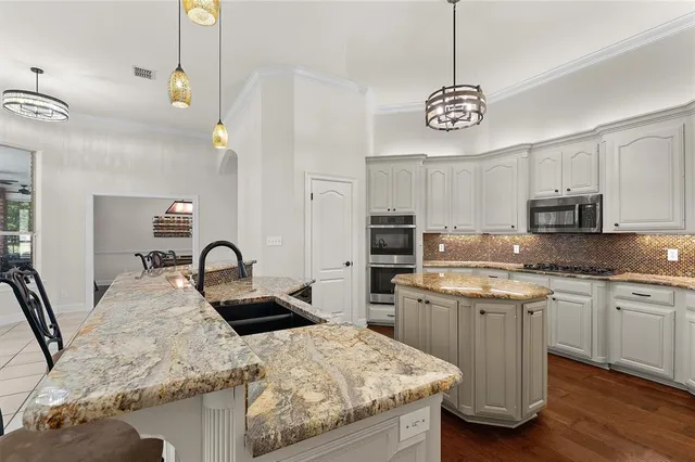 a kitchen with stainless steel appliances granite countertop a sink a stove center island and cabinets